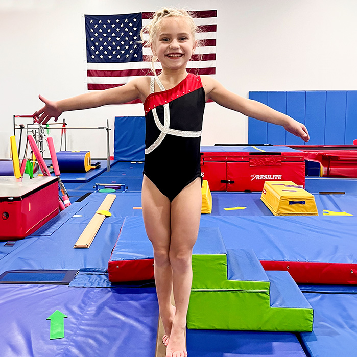 Young gymnast on balance beam practices during gymnastics class